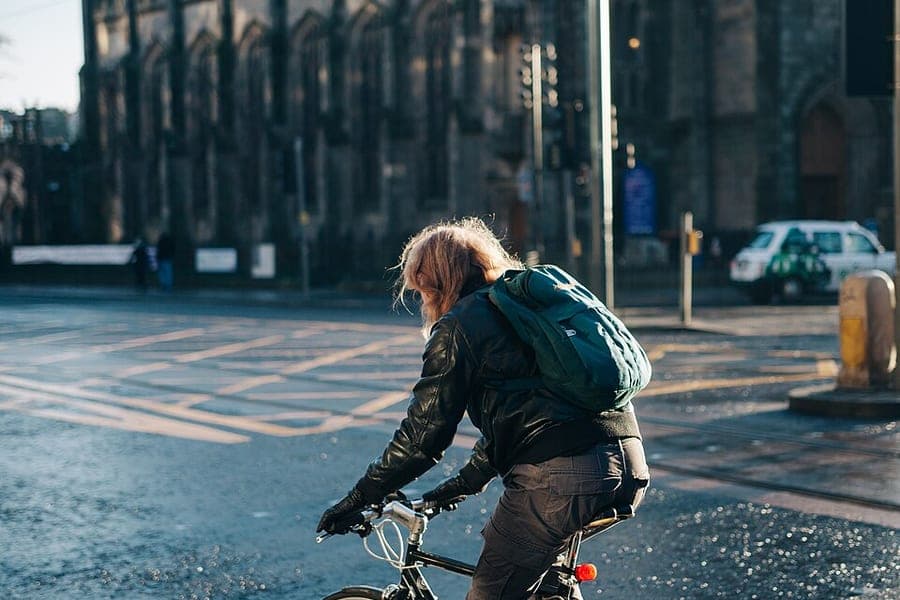 A backpack worn on the shoulders of a person walking in a city
