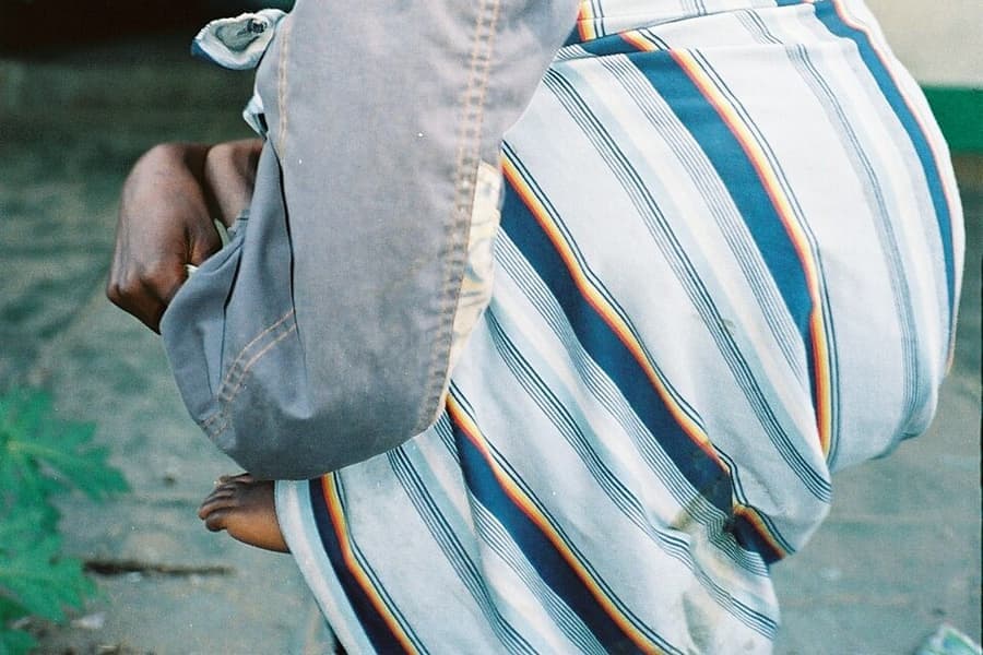 An adult carrying a child in a fabric wrap