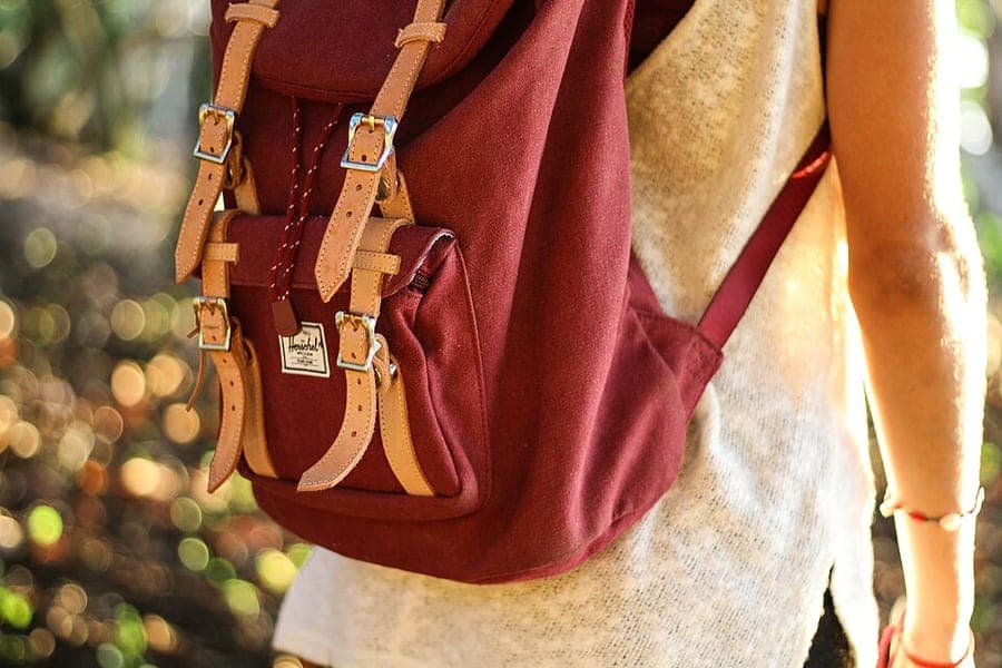 A traveler wearing a red backpack