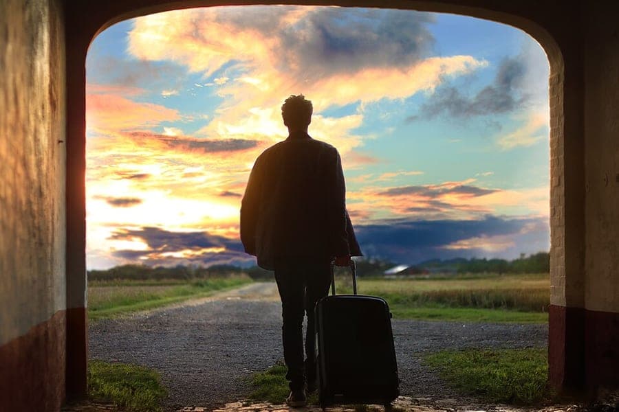 A traveler pulling a wheeled suitcase through an airport