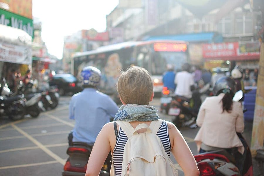 A traveler carrying a backpack through a busy city street
