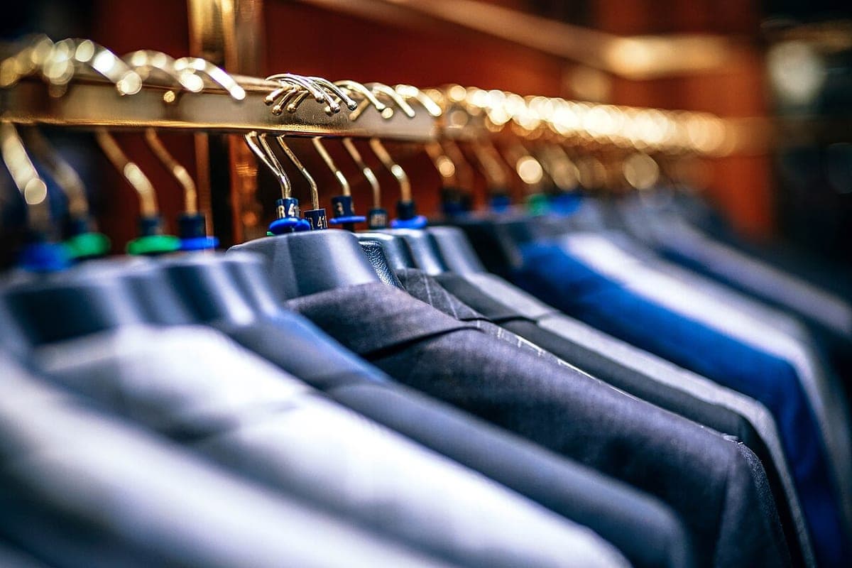 A rail of suit jackets and dress shirts on hangers