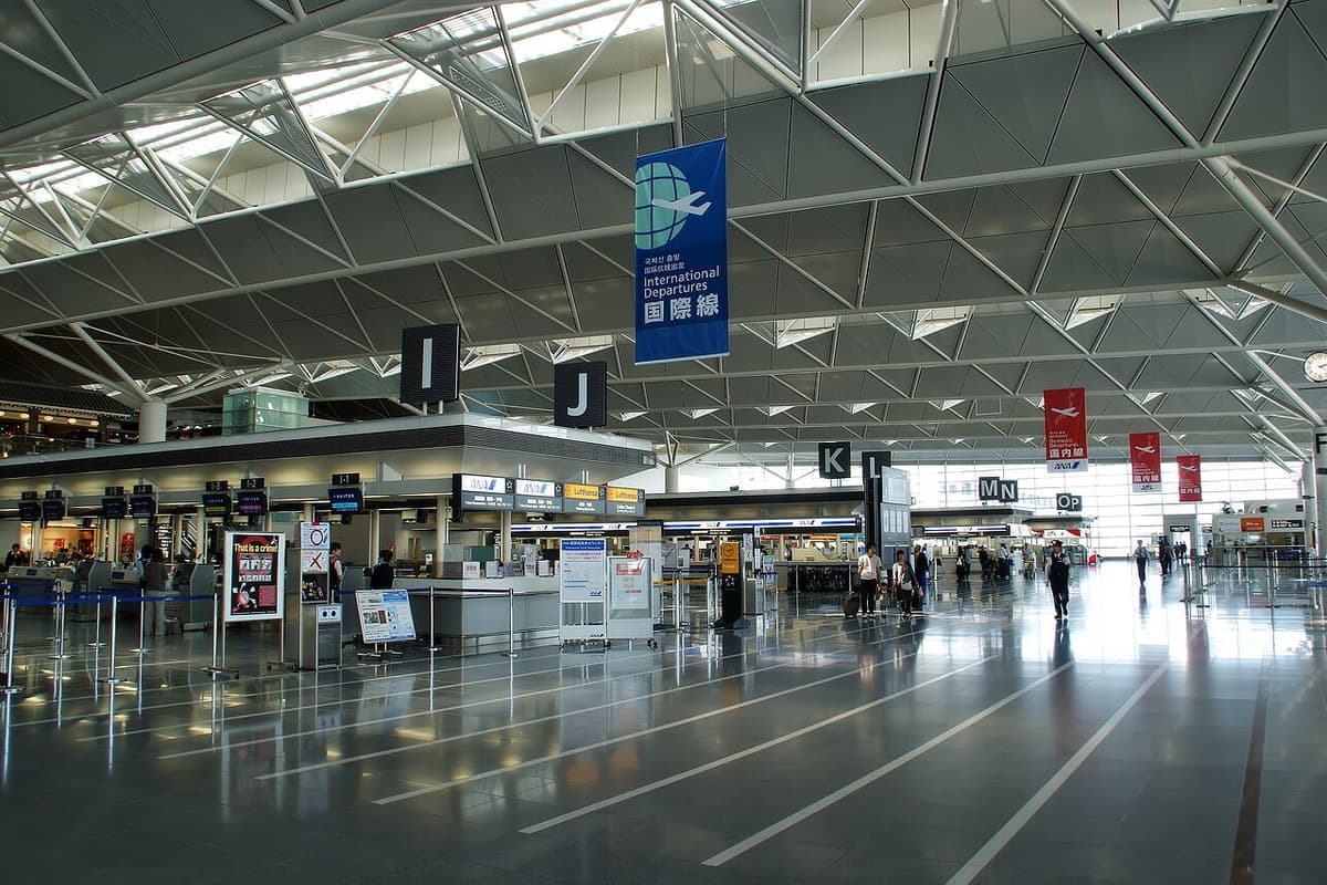 An airport check-in hall lined with bag drop counters