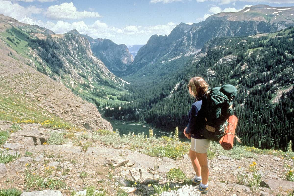 A hiker carrying a large travel backpack on a mountain trail