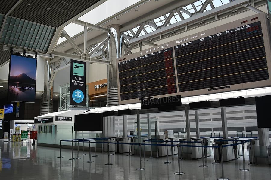 An airport departure board above a busy concourse