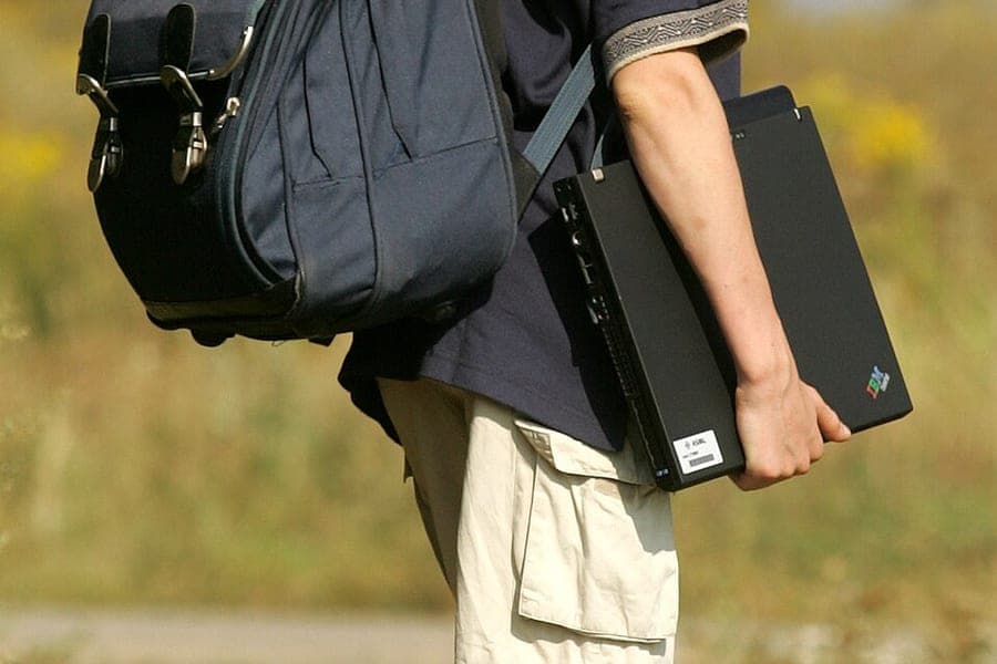 A person carrying a backpack over one shoulder