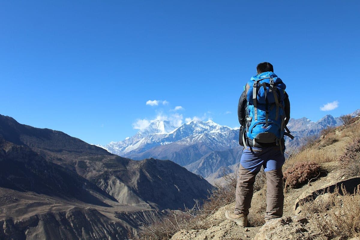 A trekker carrying a large pack on a mountain trail