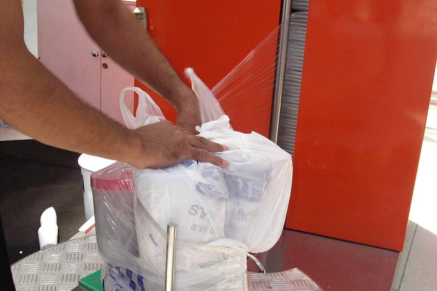 A suitcase being wrapped in protective film at an airport