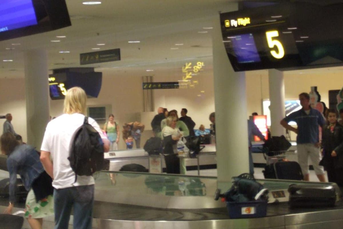 Travelers waiting at an airport baggage carousel