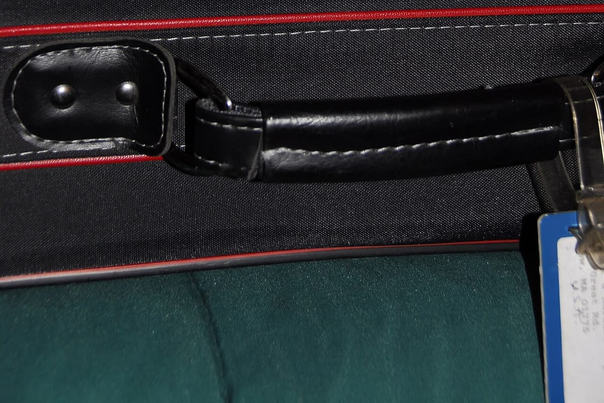 A close-up of a softside suitcase handle and luggage tag
