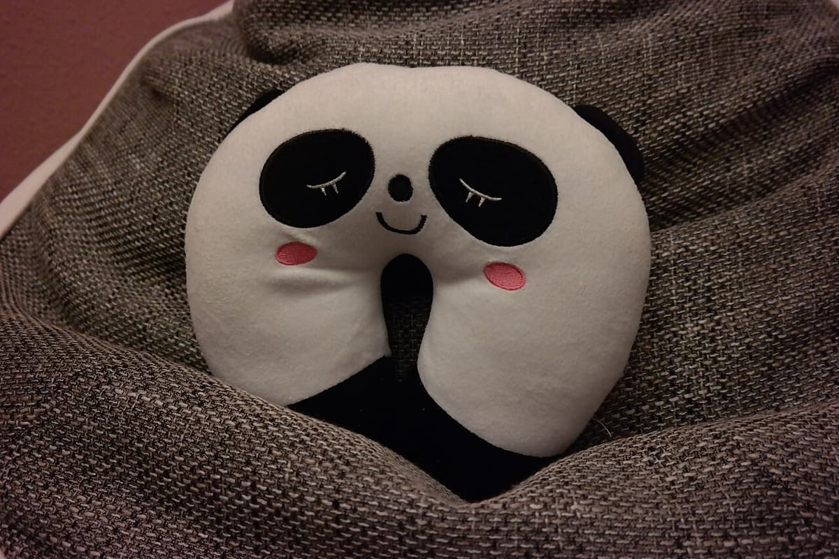 A soft travel neck pillow resting on a seat